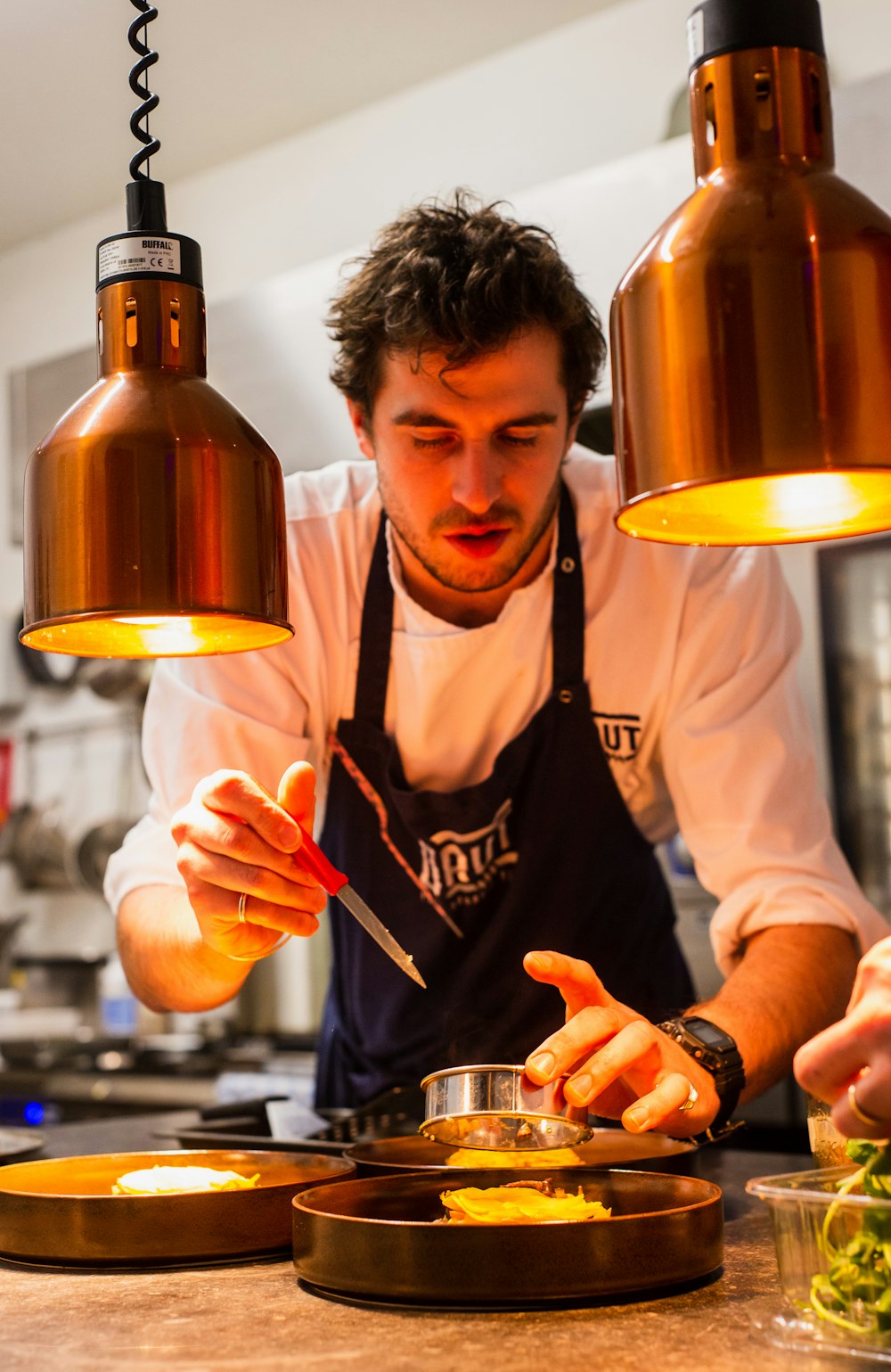 Chef Marisol plating a dish at the wood-fired kitchen pass